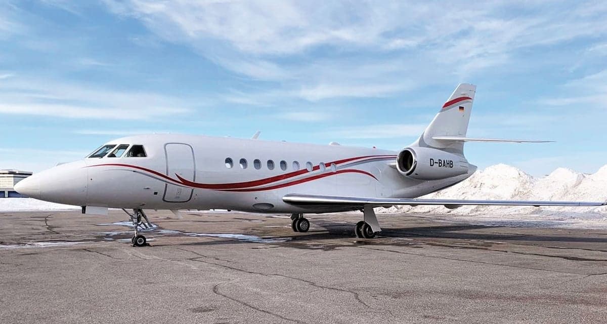 A white aircraft with red stripes parked on the tarmac.