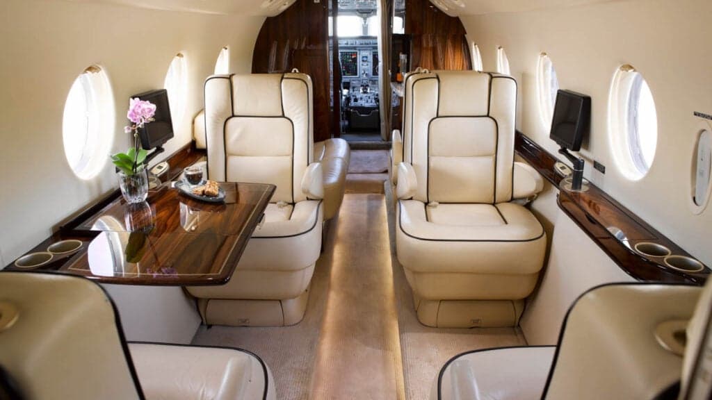 Interior view of an aircraft cabin with leather seats and wood accents.