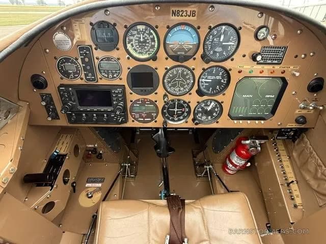 The tan-colored instrument panel of an aircraft, showing various gauges, screens, and controls.