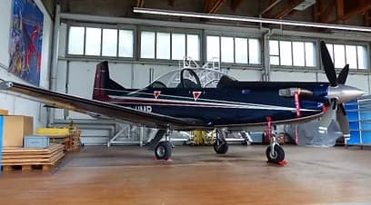 Side view of a blue and silver aircraft in a hangar.