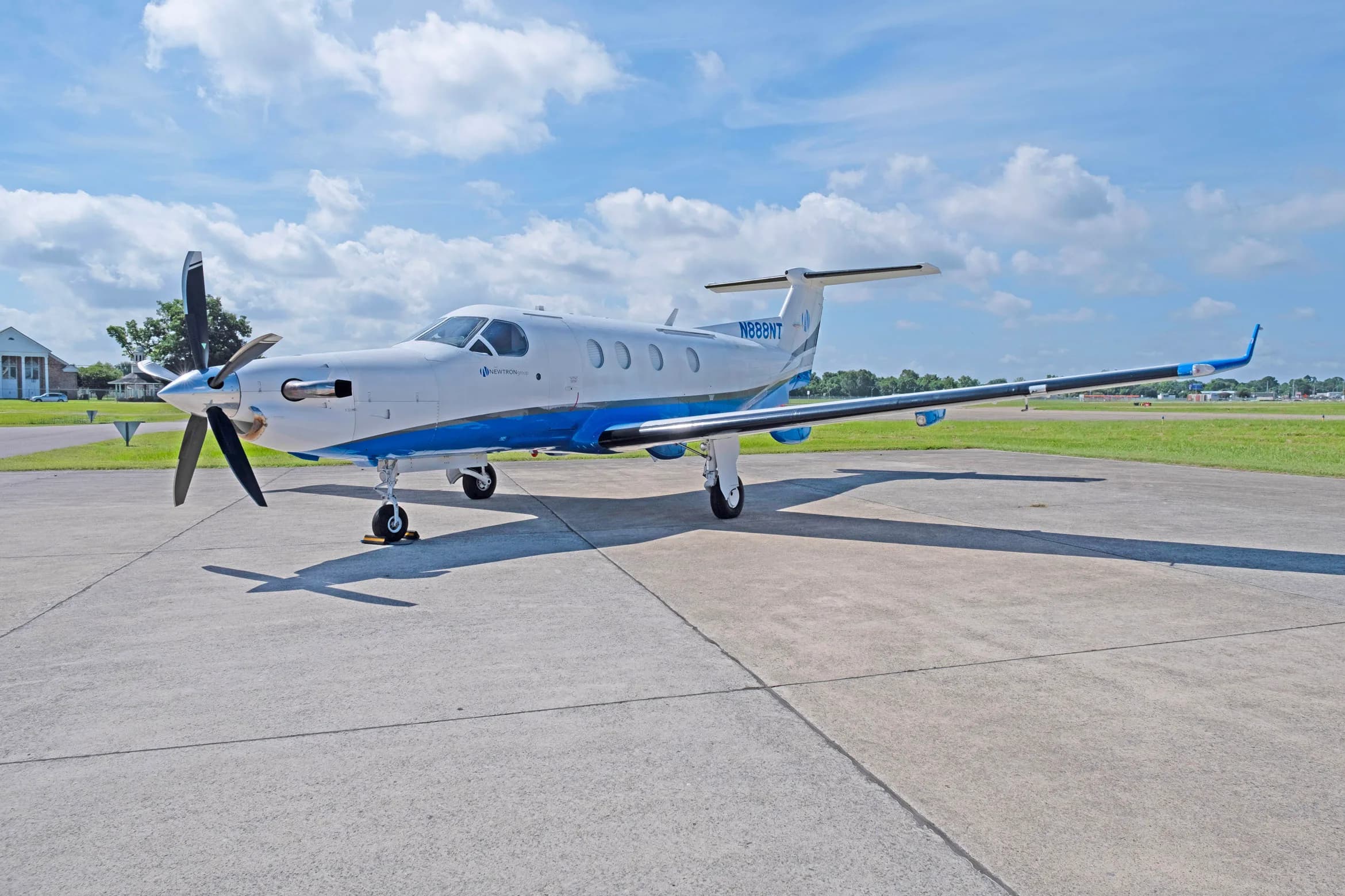 A white and blue Pilatus PC-12 aircraft, tail number N888NT, parked on a tarmac with its propeller visible.