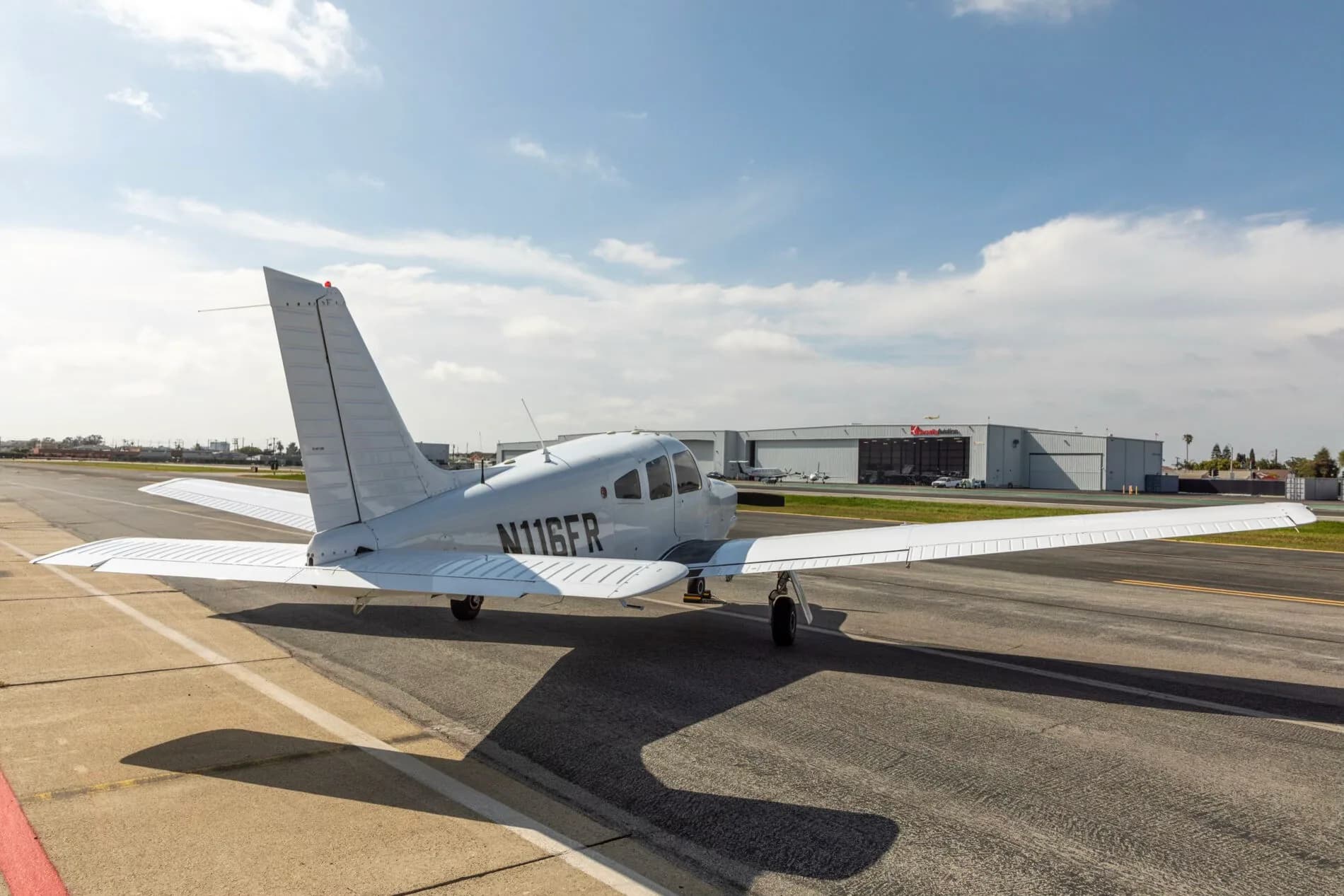 A rear-left view of a white Piper PA-28-181 Archer III aircraft, registration N116FR, parked on an airfield.