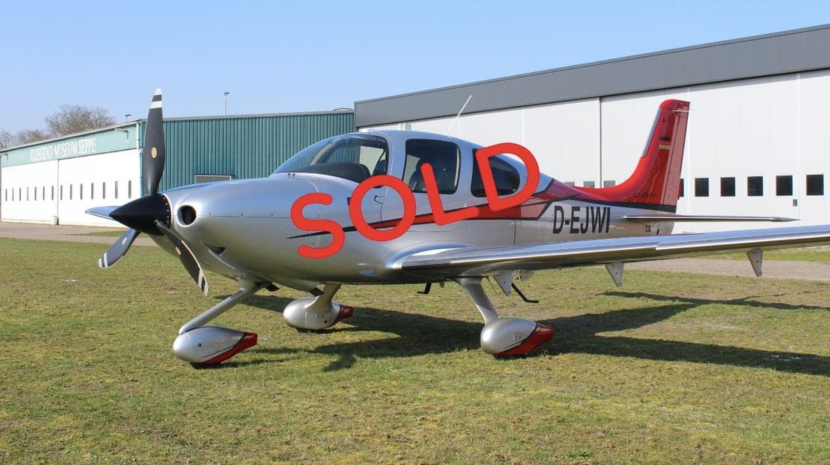 A Cirrus SR22 aircraft with registration D-EJWI is parked on the grass.