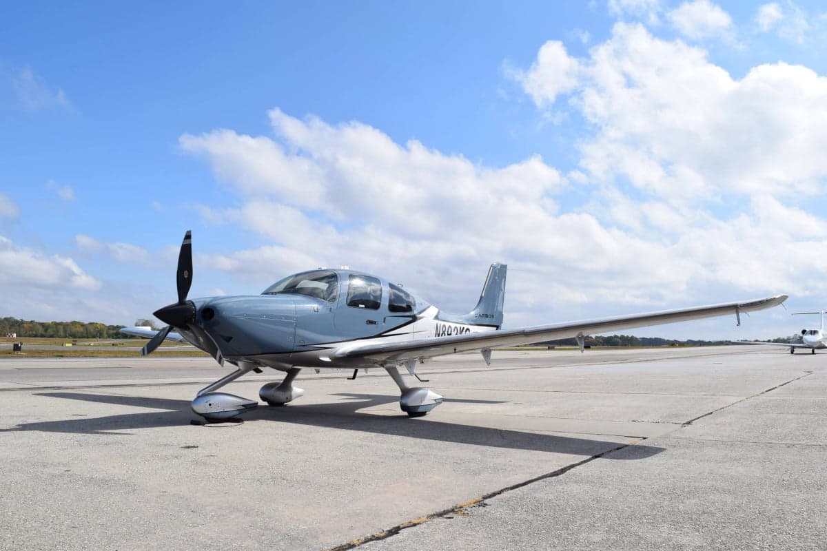 A Cirrus SR22T aircraft with a blue and silver paint scheme is parked on the tarmac.