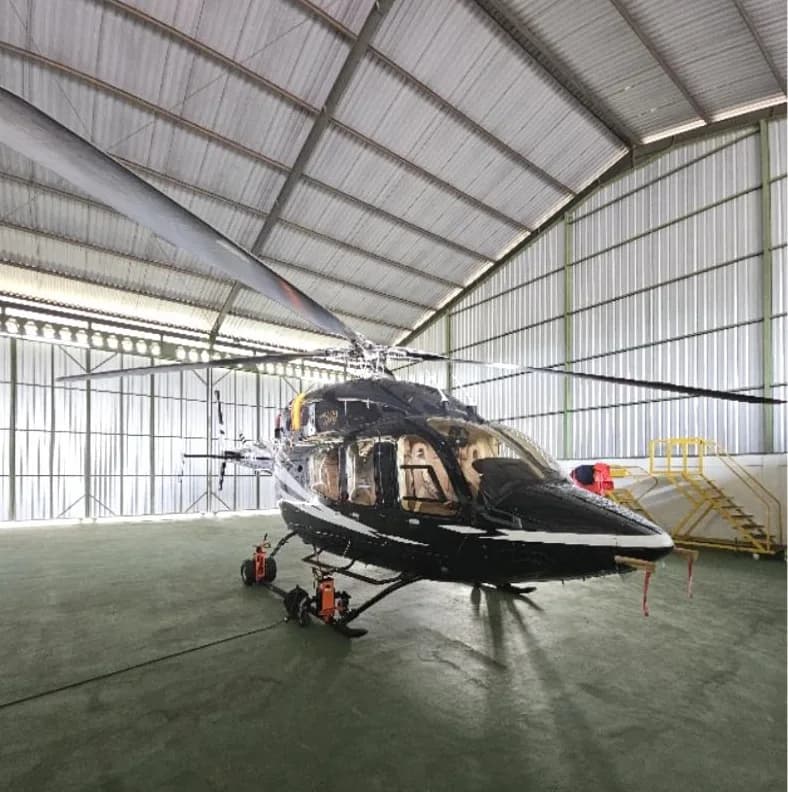 Front view of a black and white helicopter inside a hangar.