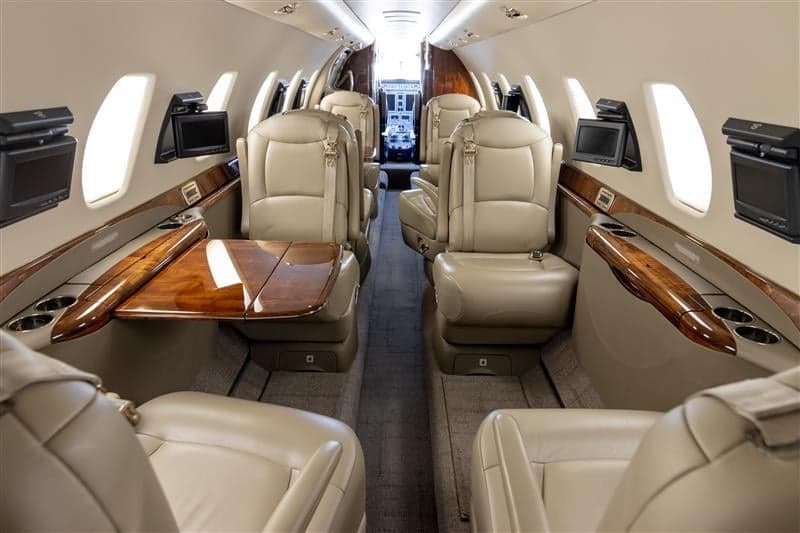 The aircraft's interior features leather seats, wood accents, and individual entertainment screens.