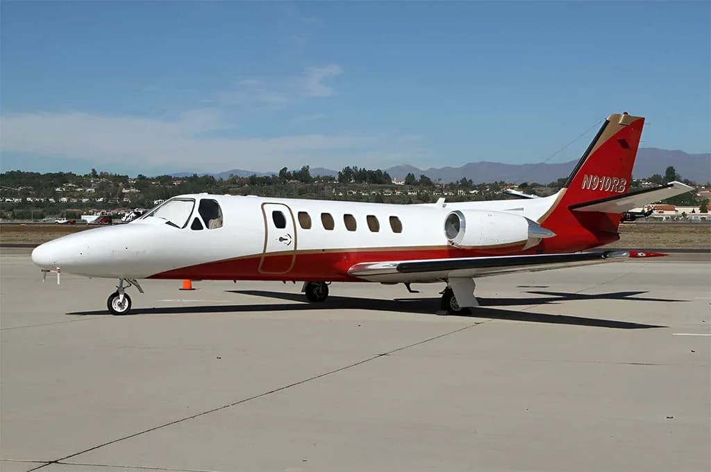 A white and red Cessna Citation business jet, tail number N910RB, parked on an airfield under a clear sky.