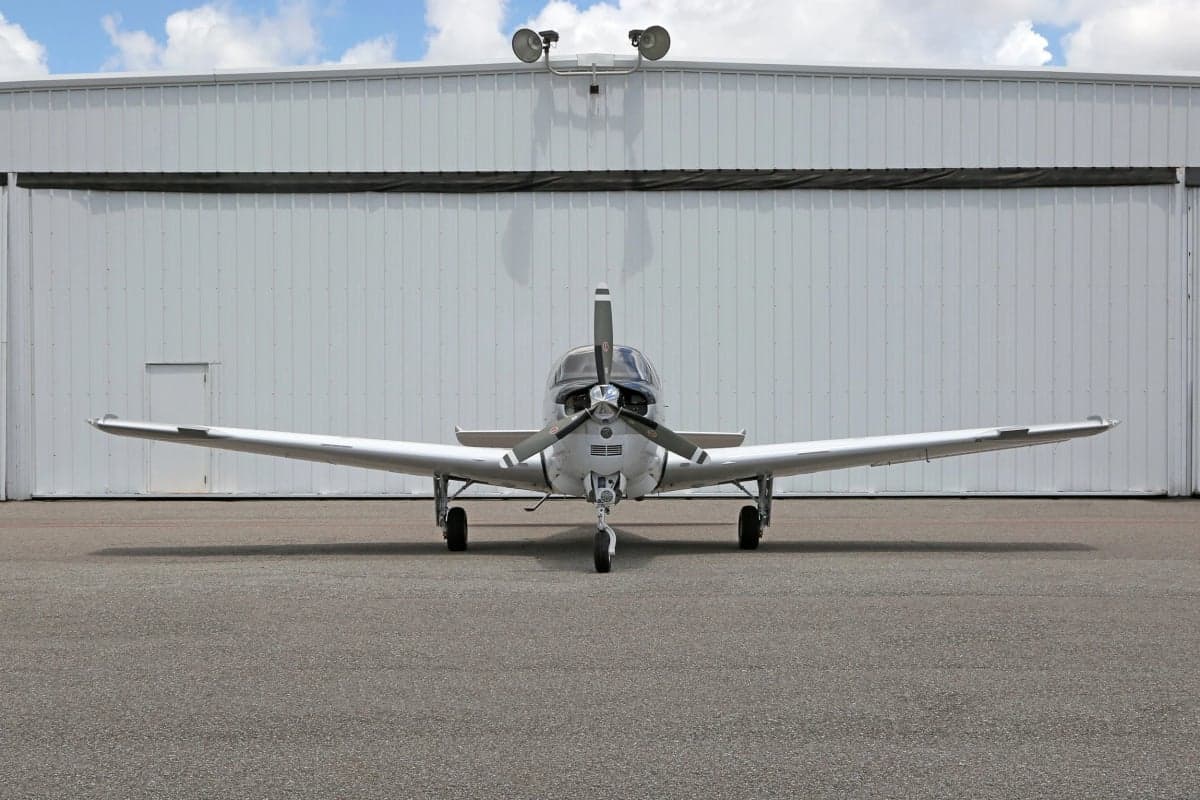 Front view of a Beechcraft Bonanza aircraft parked in front of a hangar.