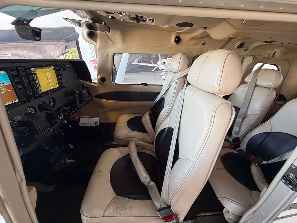 A view of the aircraft's tan and black leather interior cabin, showing the front and rear seats and part of the cockpit.