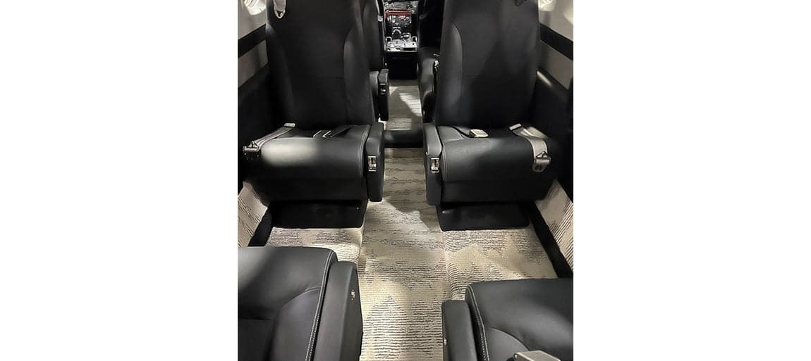 View of the aircraft interior showing the black leather seats and carpeted floor.