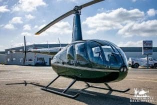 Robinson R44 helicopter on the tarmac with a dark green paint scheme.