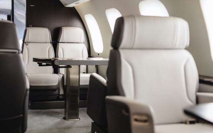 A view down the aisle of the Global 7500 cabin, showing the seating arrangement and tables.