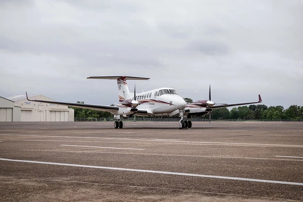A front view of the N367TP twin-engine turboprop aircraft, white with maroon accents, parked on an airfield.