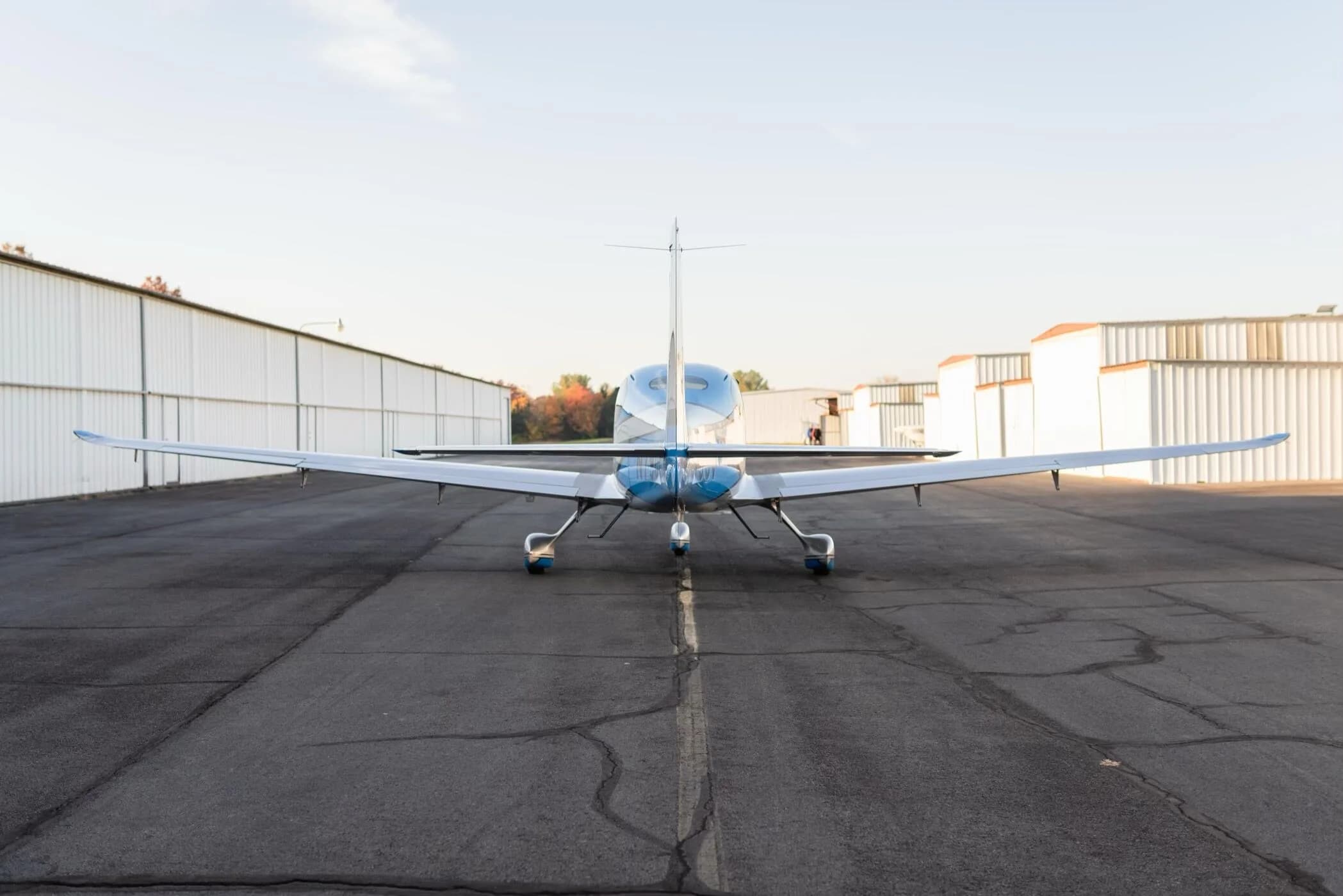 A rear view of the blue and silver Cirrus SR22T GTS aircraft, registration N79CV, parked on an airfield.