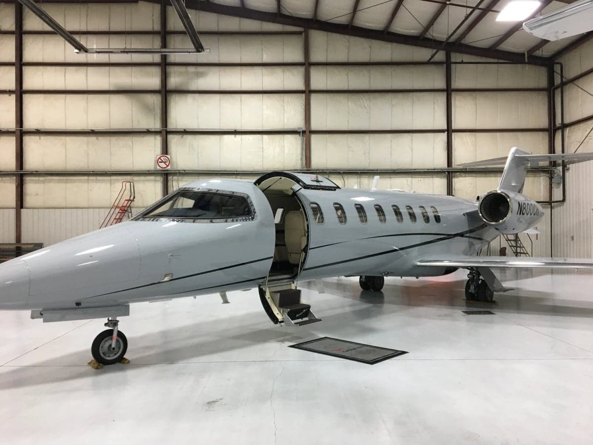 A gray aircraft, N800CH, is parked inside a hangar with the door open.