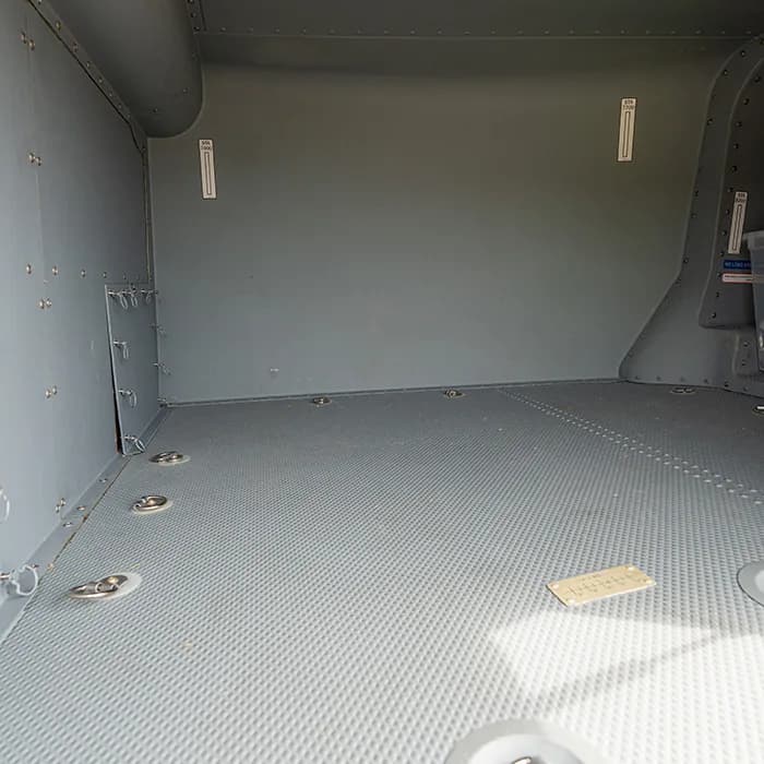 Empty cargo area of the helicopter with a gray floor and metal walls.