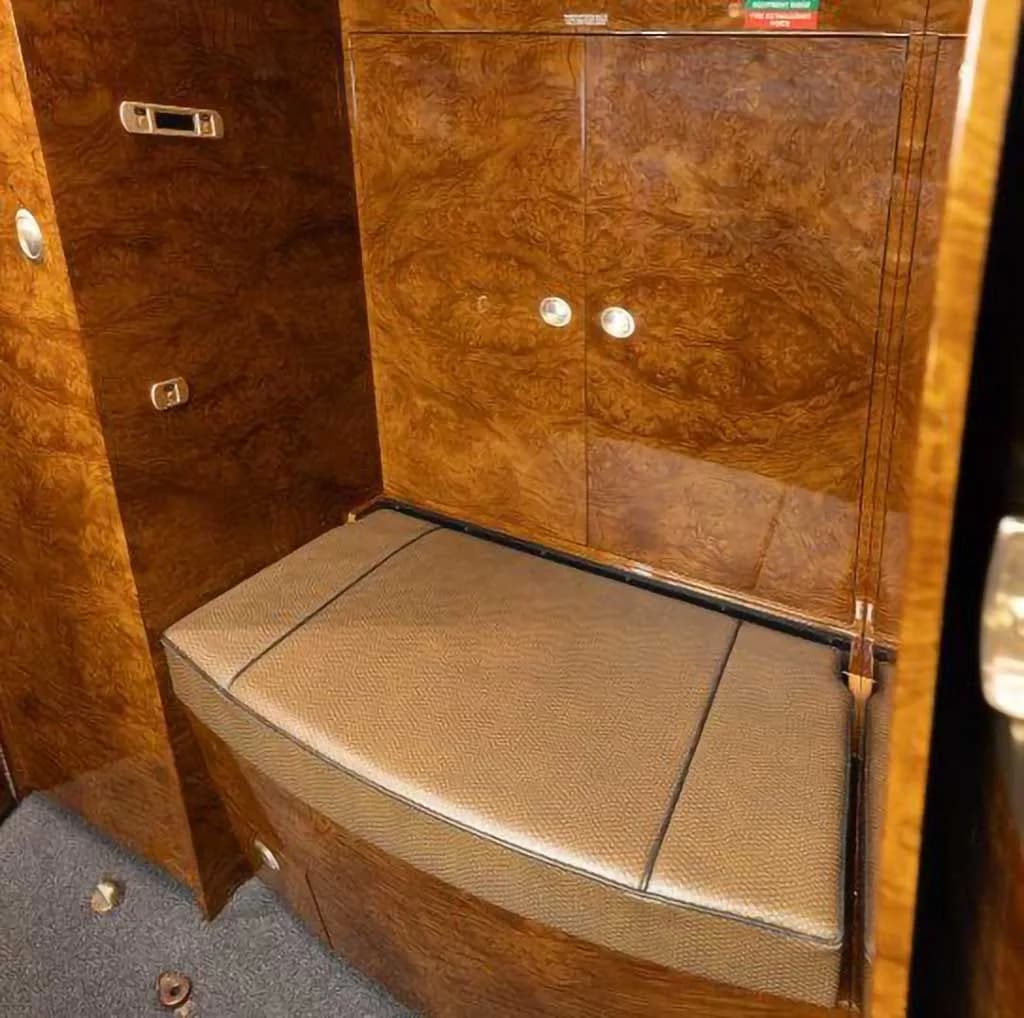 A small upholstered bench seat surrounded by luxurious wood paneling in the aircraft interior.