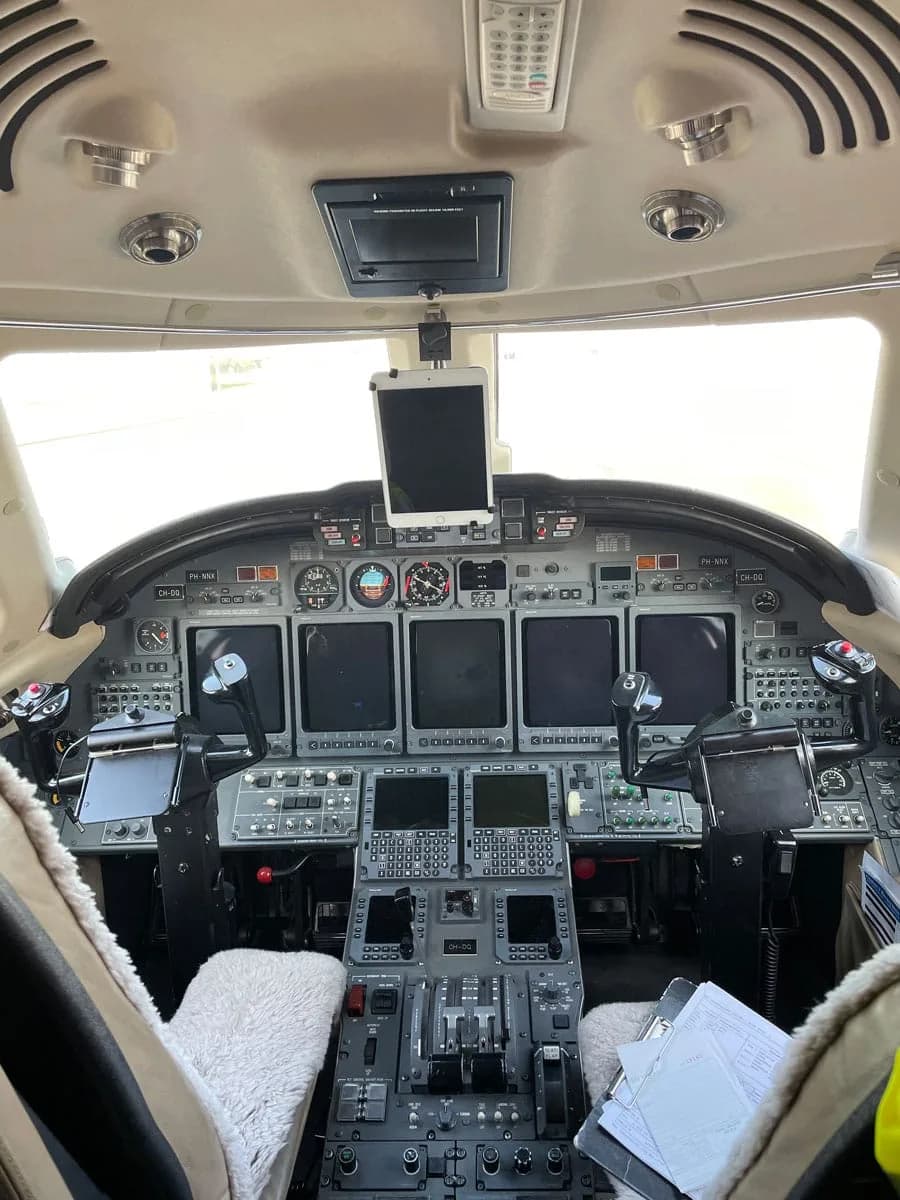 The cockpit of a private jet with multiple screens, controls, and an iPad mounted.