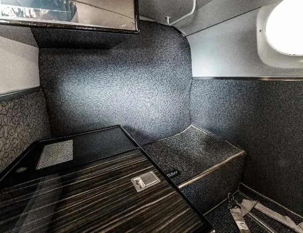 A close-up view of a dark patterned wall and a storage compartment in the aircraft's cabin.