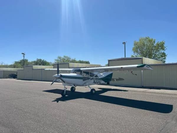 A white and green Maule aircraft, registration N20RD, parked on a tarmac with sun flare.