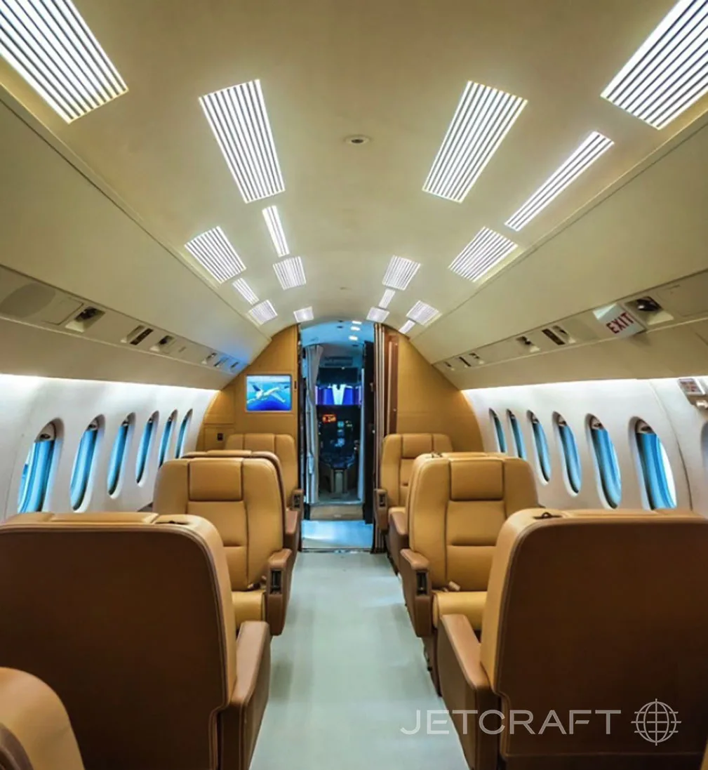 A view down the aisle of a business jet cabin with tan leather seats.