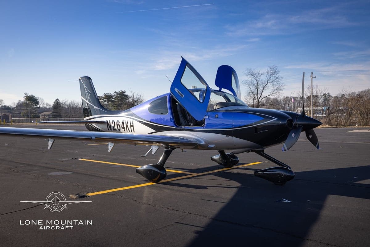 A Cirrus SR22T aircraft with registration N264KH parked on the tarmac with the doors open.