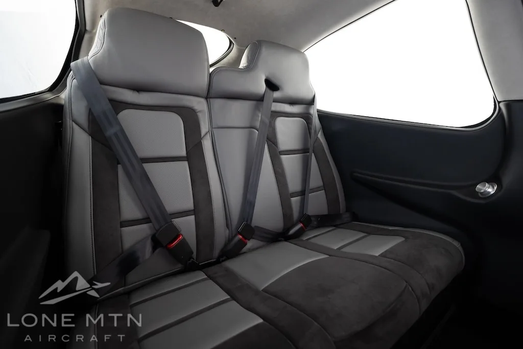 A wider view of the gray and black rear passenger seats of a Cirrus SR22T aircraft, with seatbelts visible.