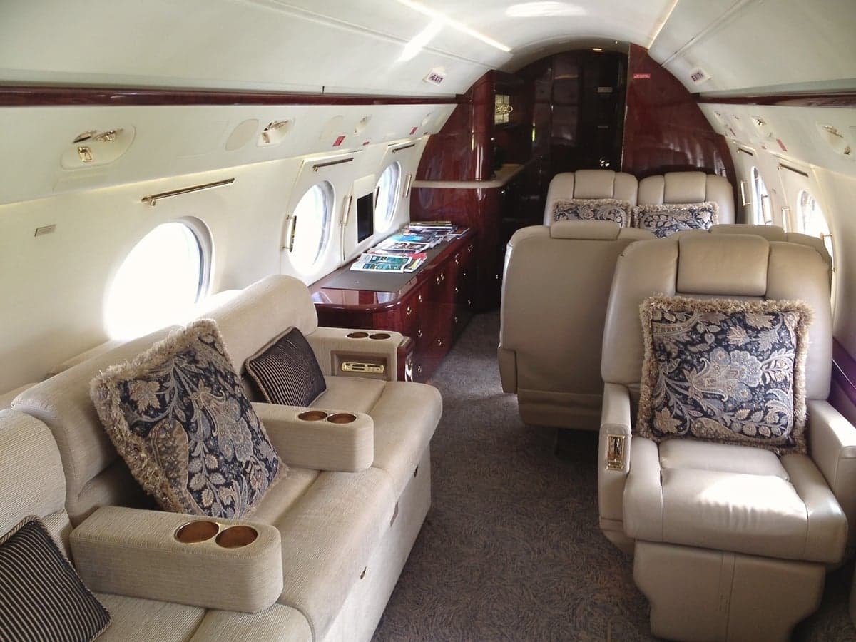Interior of the aircraft featuring leather seats and decorative pillows.