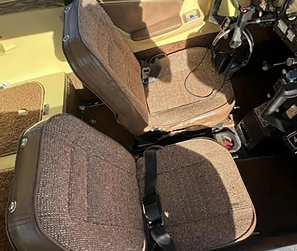 The brown fabric and leather seats of a small aircraft cabin.