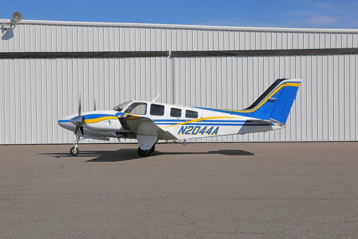 Side view of a Piper PA-31 Navajo Chieftain aircraft with registration N2044A parked on the tarmac in front of a hangar.