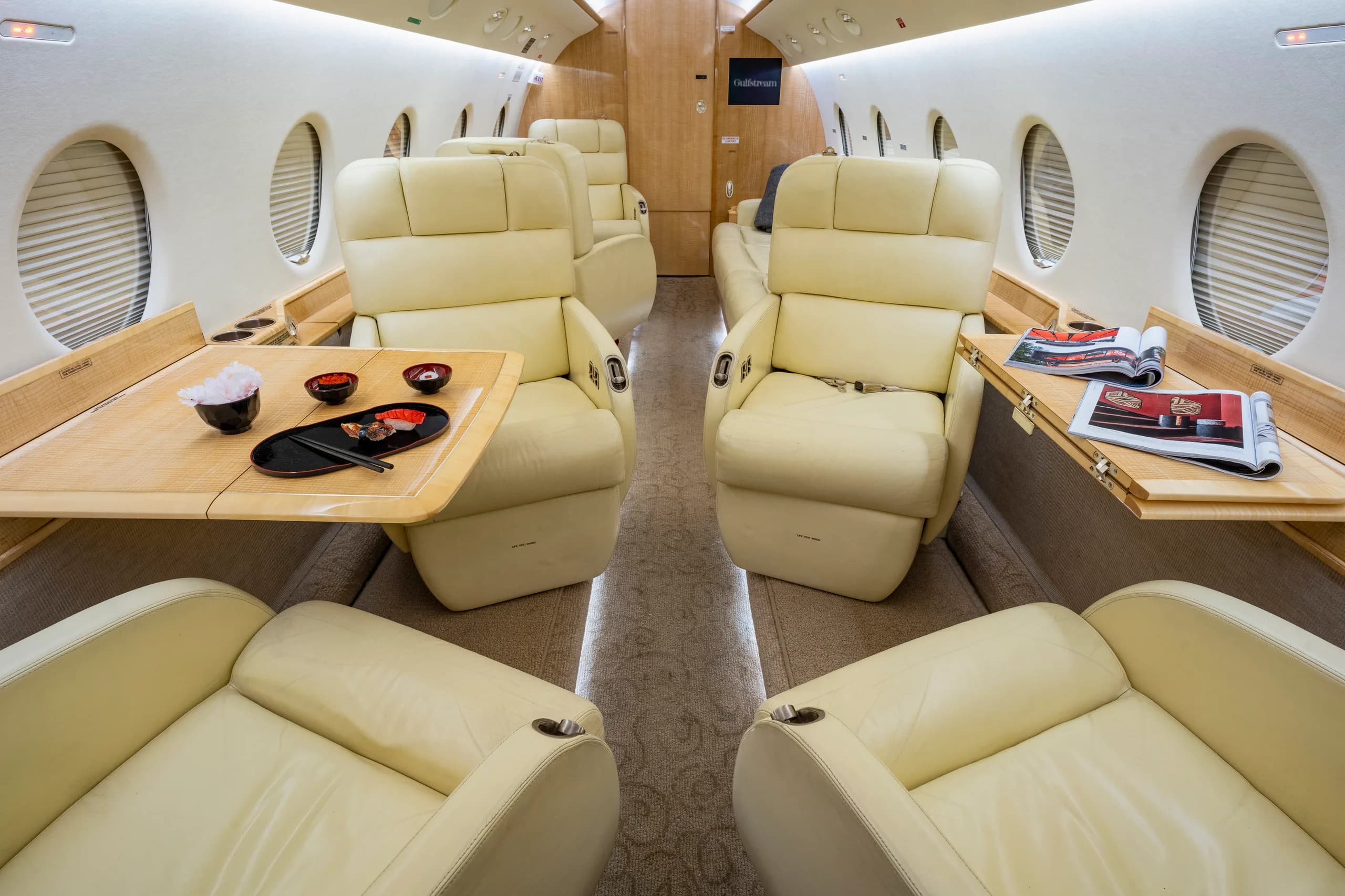 The aircraft's interior features cream-colored leather seats and wood accents.