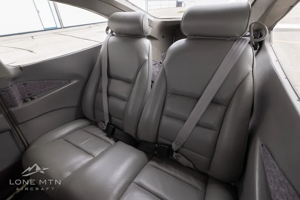 The grey leather rear passenger seats of a small aircraft cabin.