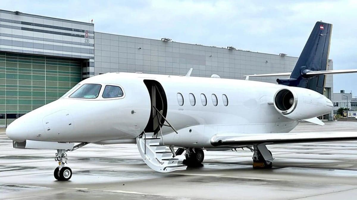 A white Cessna Citation CJ4 aircraft with the door open on the tarmac.