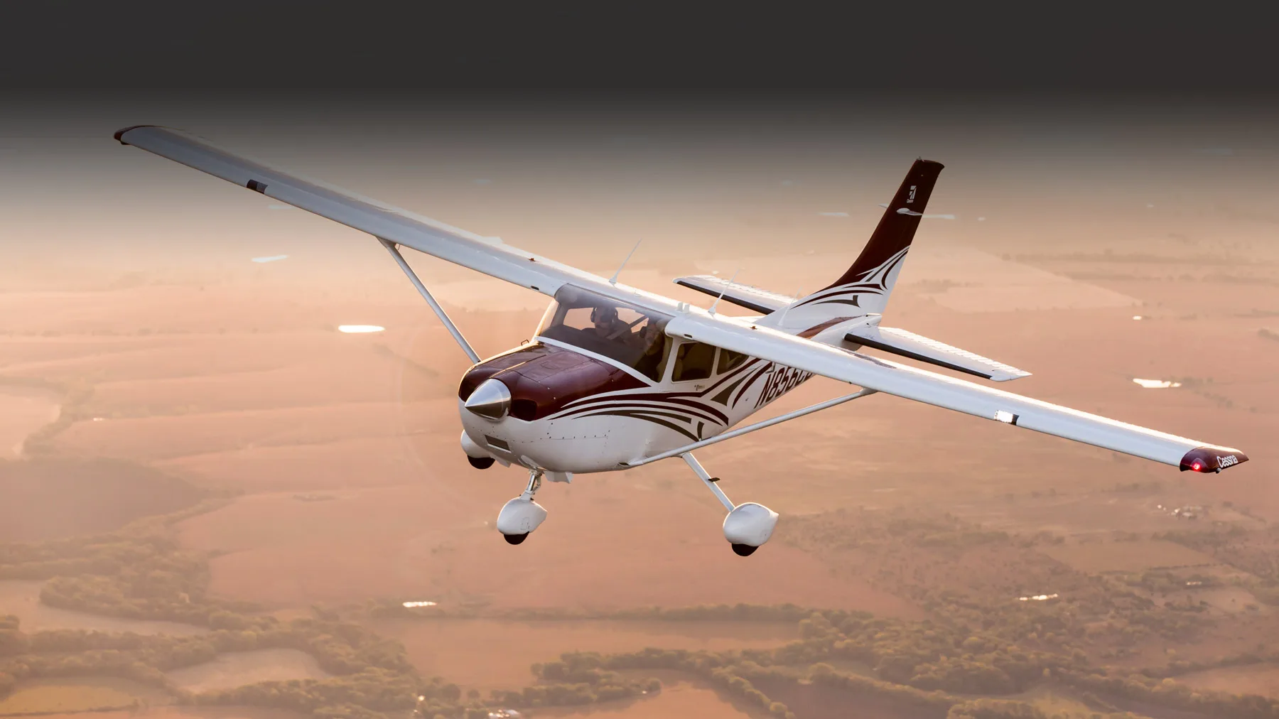 A Cessna 206 Stationair in flight, showcasing its maroon and white paint scheme and N654TD registration.