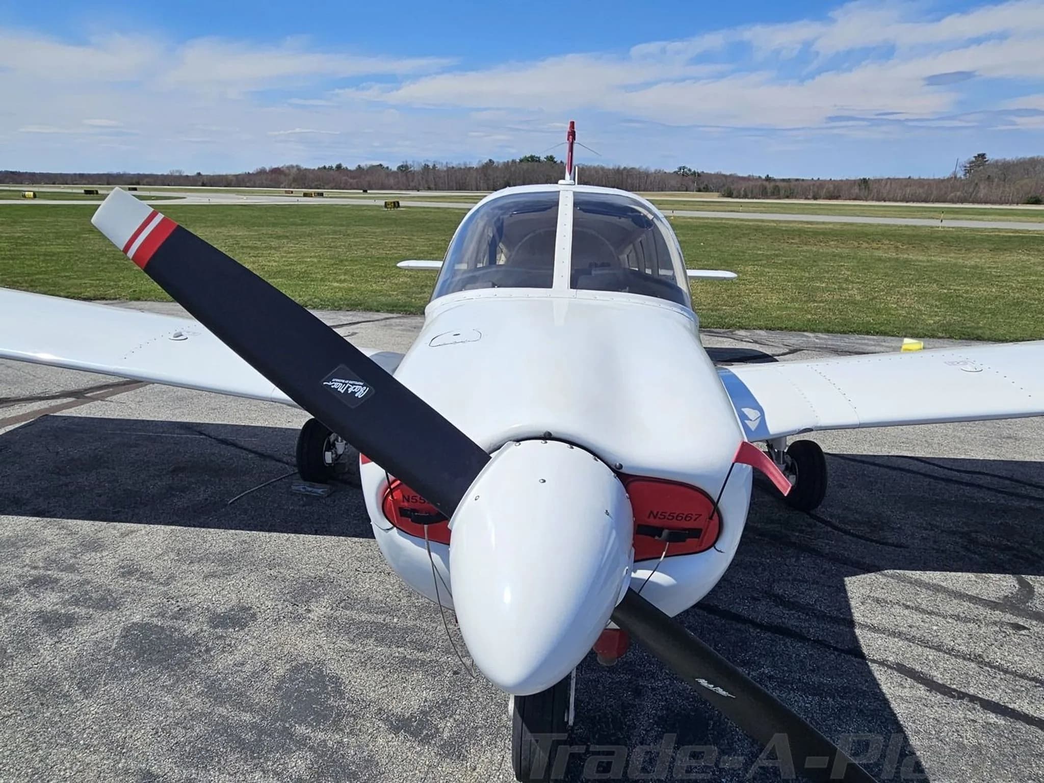 Close-up front view of a white and maroon Piper PA-28 aircraft, showing the propeller and nose.