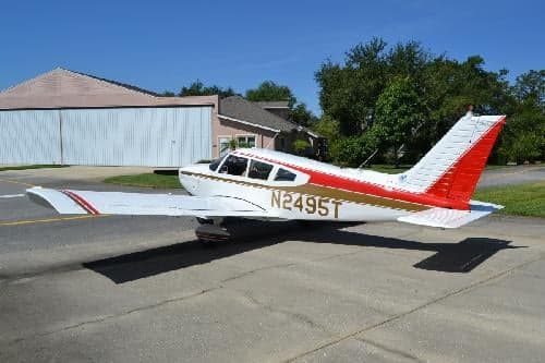 Piper PA-28-181 Archer II, registration N2495T, parked on the tarmac with a hangar in the background.