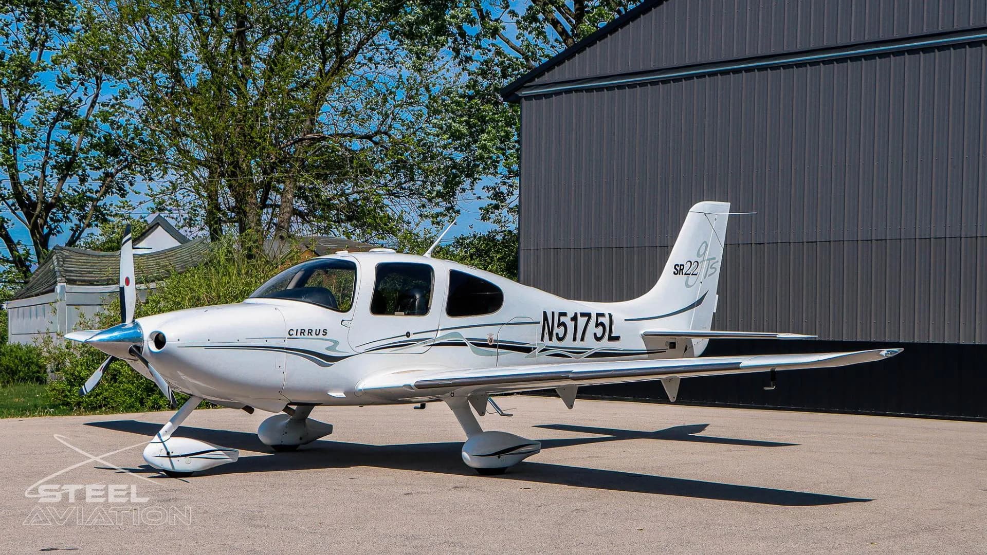 Left side view of a white Cirrus SR22 aircraft (N5175L) with black and grey livery, parked on an airfield.