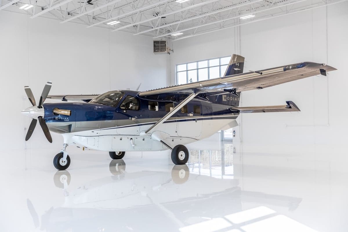 A Kodiak 100 aircraft with registration C-FWKB parked in a hangar.