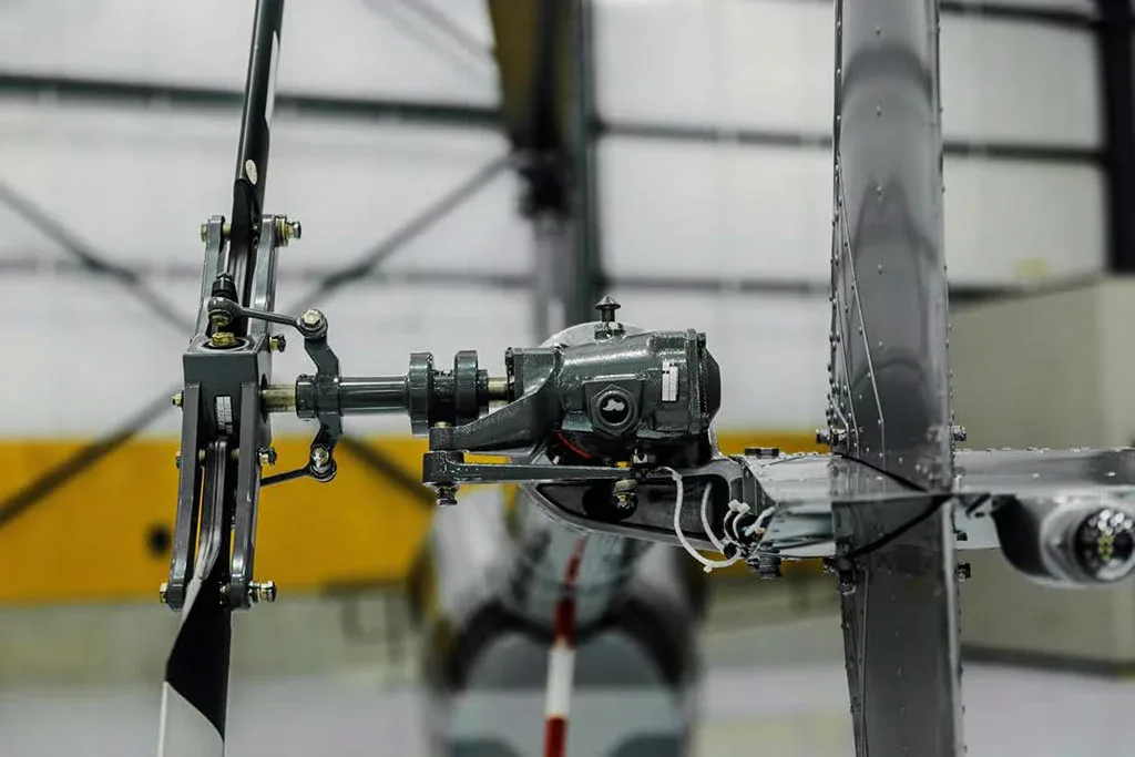 A detailed close-up of the tail rotor gearbox and mechanism of a grey helicopter.