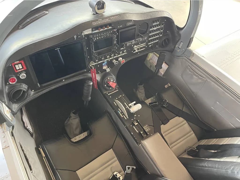 The cockpit of the aircraft, showing the instrument panel with multiple screens and controls, and the front seats.