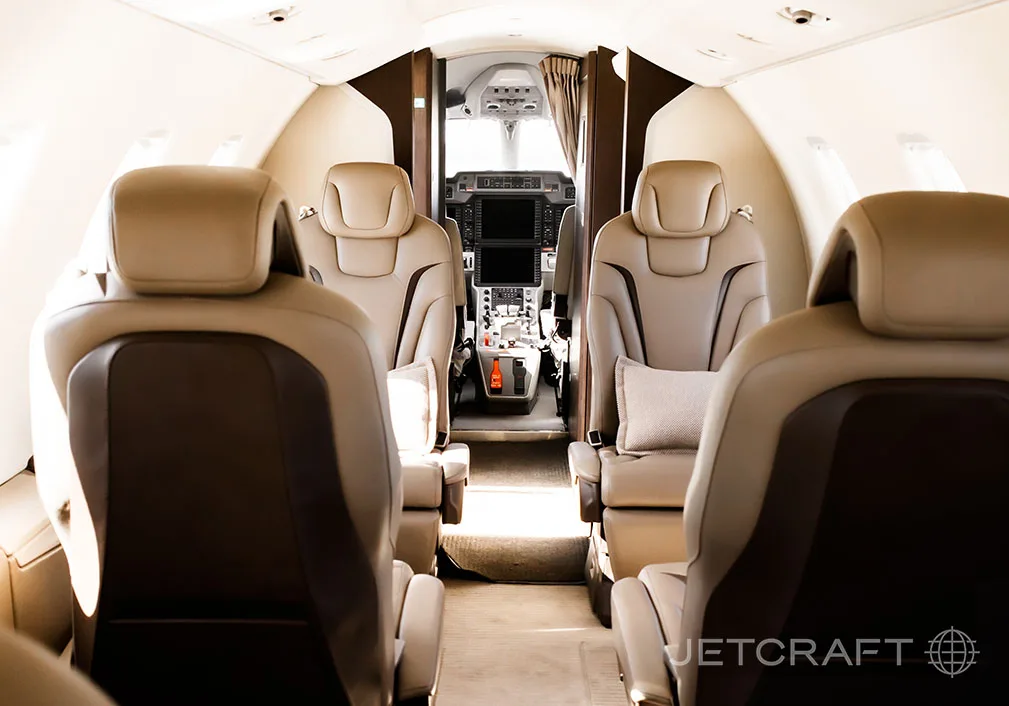 A view from the rear of the aircraft cabin looks forward through the aisle towards the cockpit.