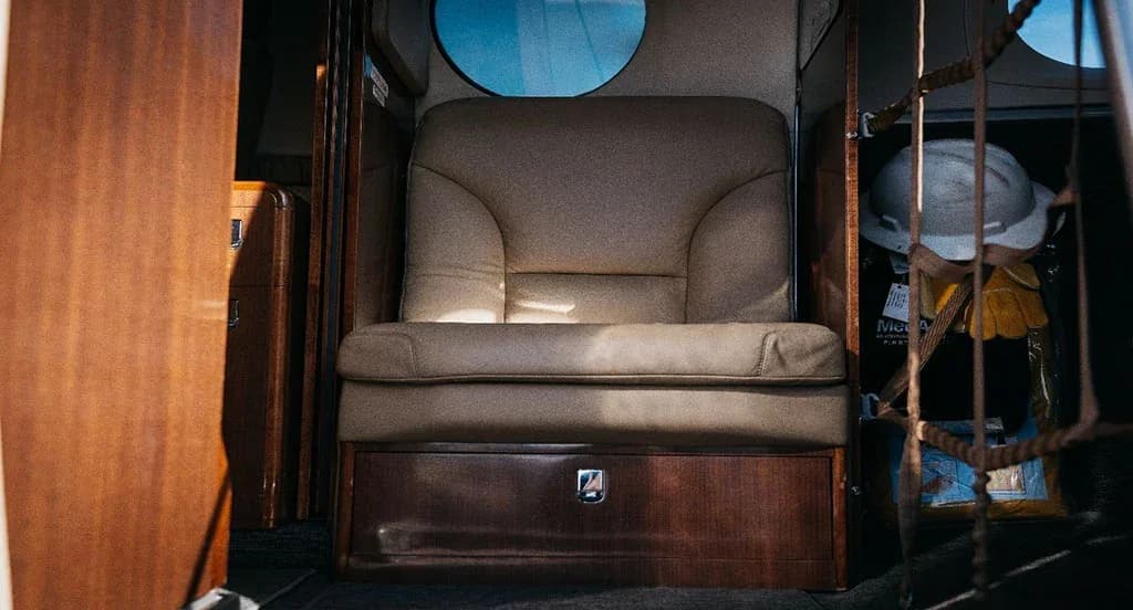 A single tan leather seat with a wooden base inside the aircraft cabin.