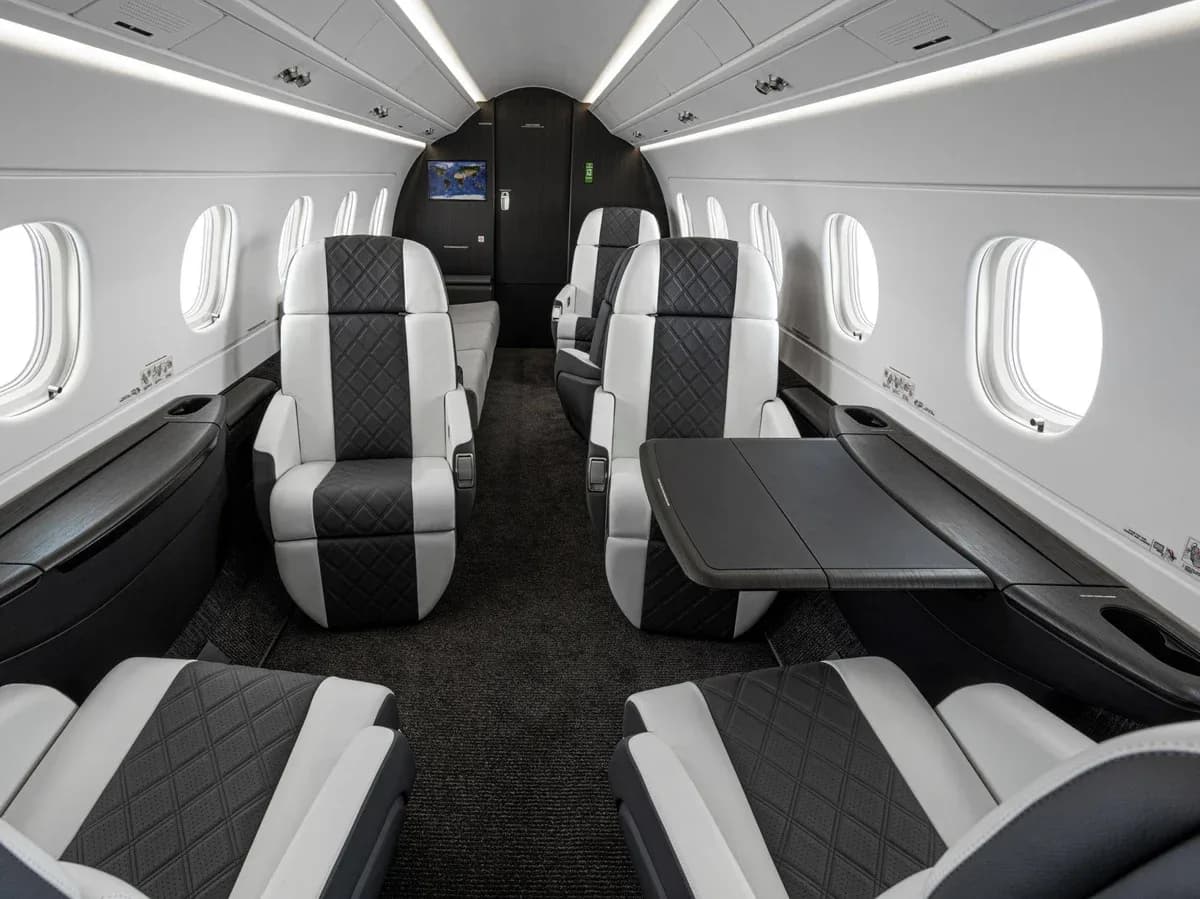 The interior of a business jet with leather seats and a table.