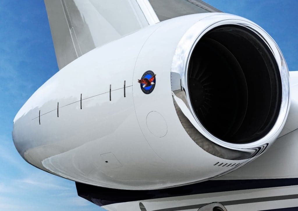 Close-up of a business jet engine with a logo on the side.