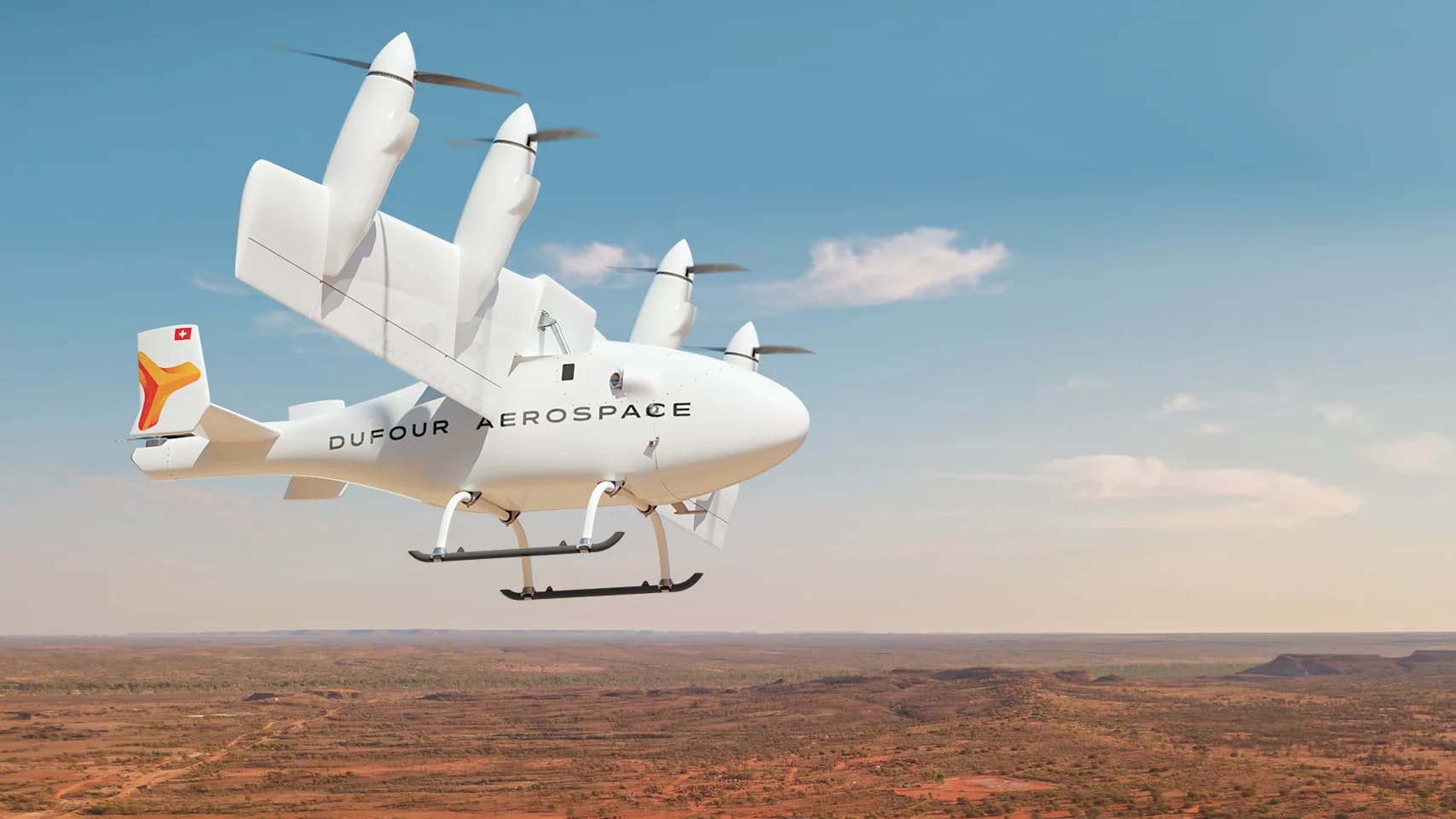 A white Dufour Aerospace eVTOL aircraft with orange accents flying over a vast desert landscape under a blue sky.