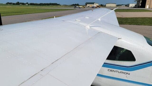View of the wing of a Cessna Centurion aircraft with a blue and white paint scheme.