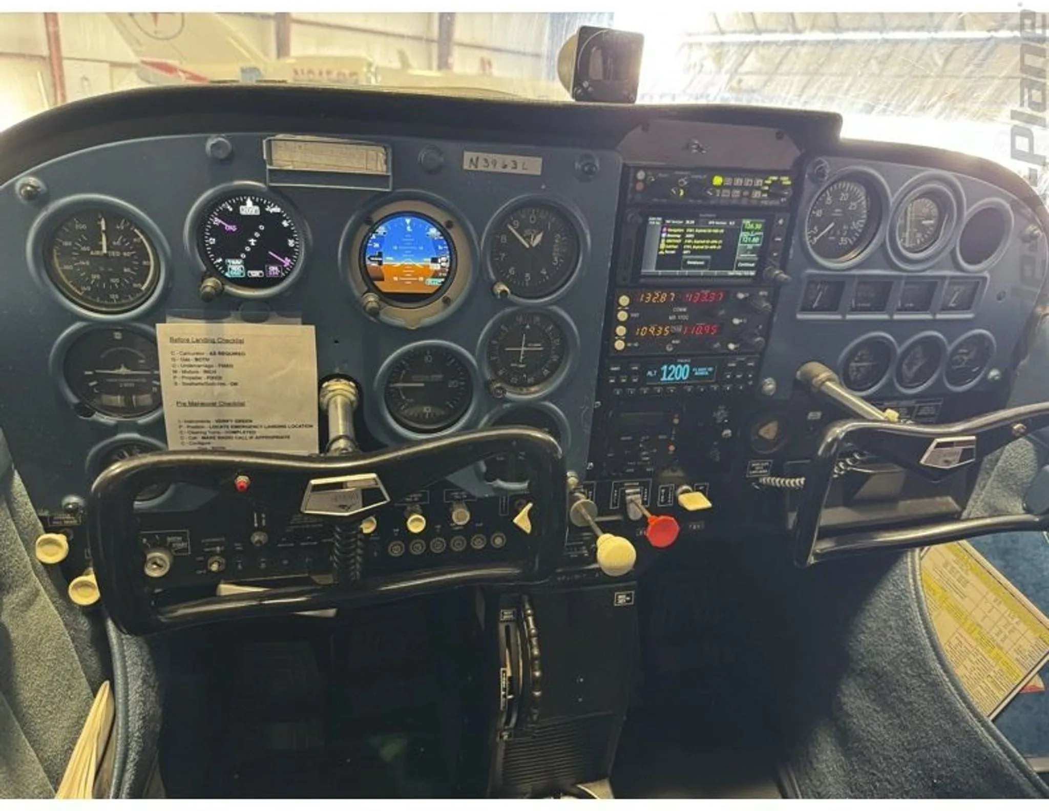 The cockpit instrument panel of a Cessna 172, showing various gauges, avionics, and the control yoke.