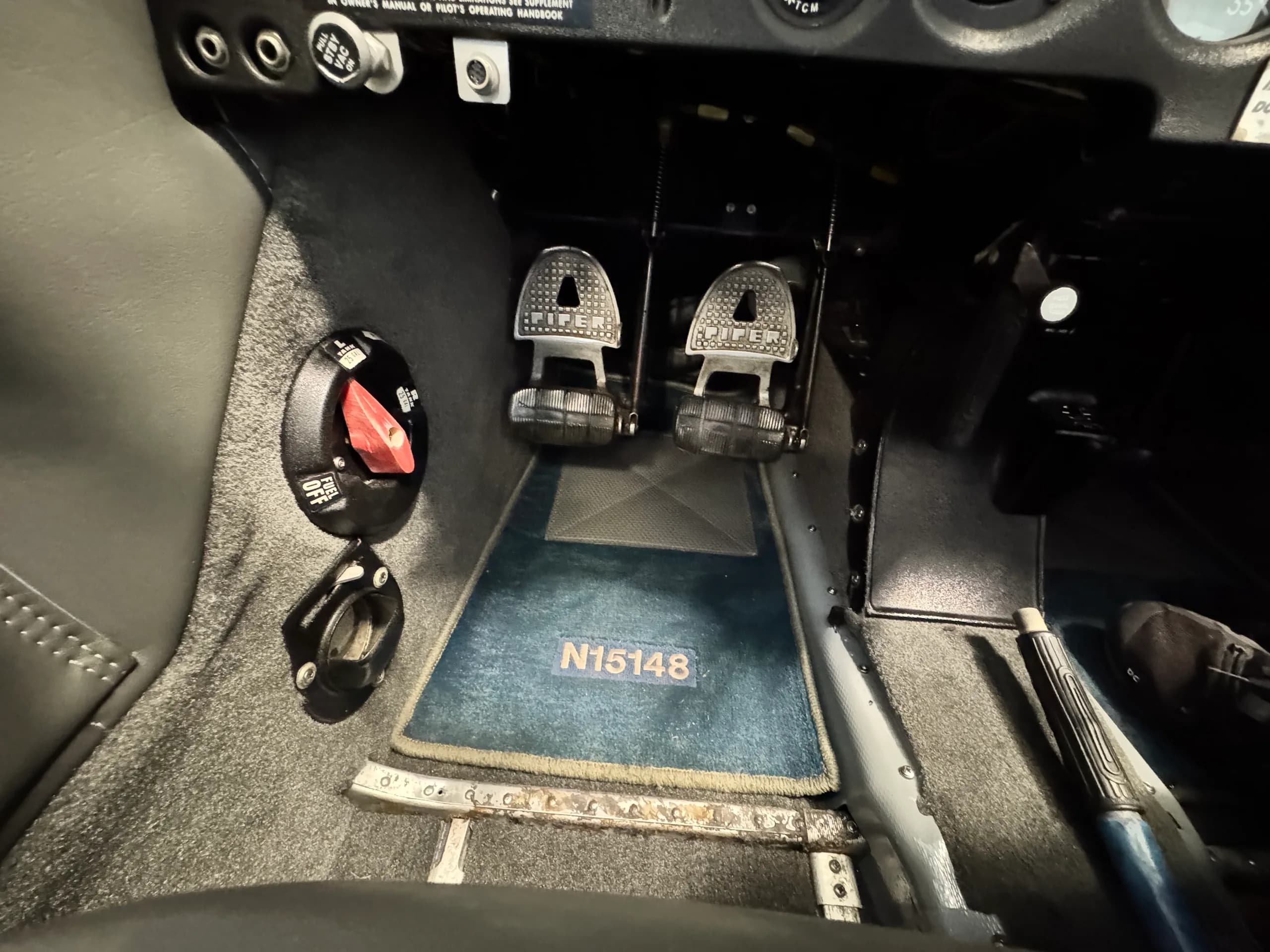 Close-up view of the rudder pedals and floor mat with "N15148" embroidered, inside the aircraft cockpit.