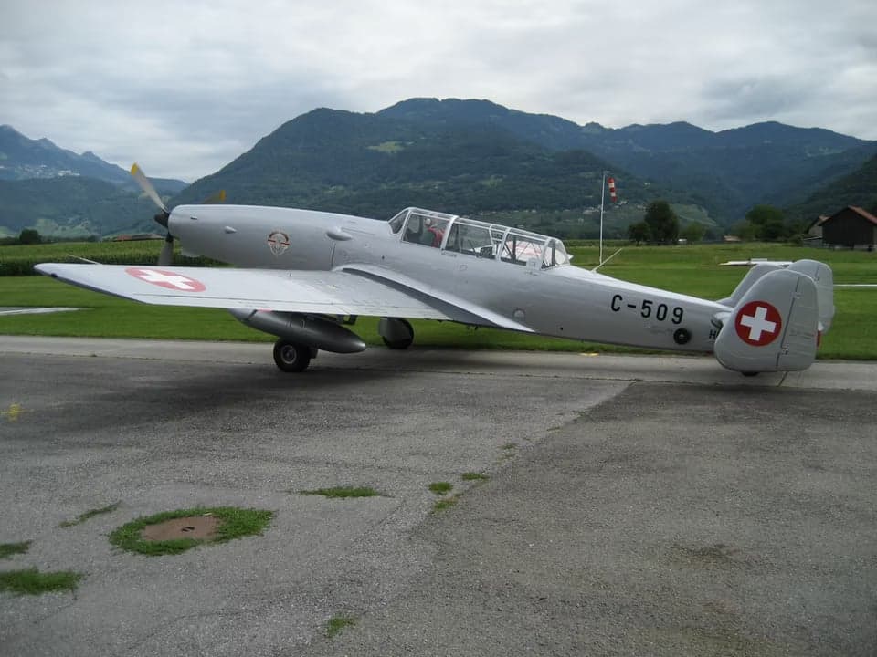 Two P-3 Pilatus aircraft in flight, one with yellow wings.