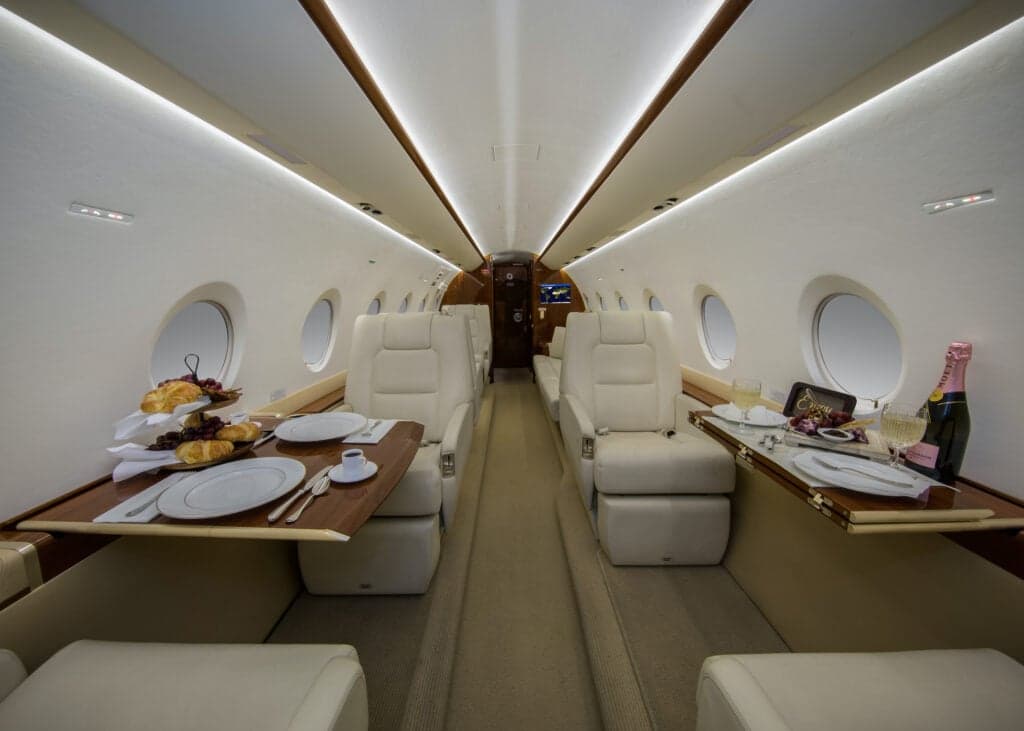 Interior view of the aircraft cabin with two white leather seats.